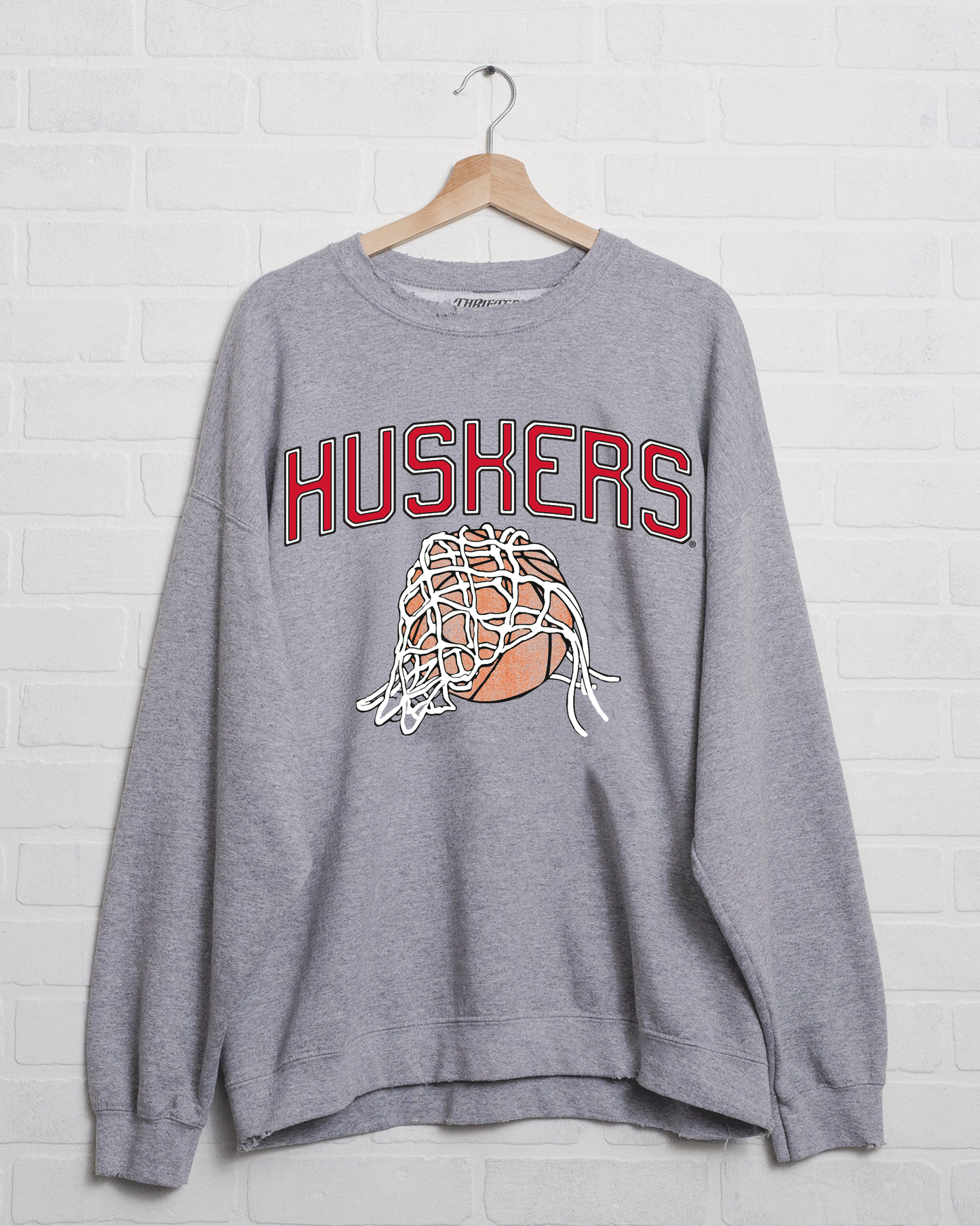 Gray sweatshirt with "HUSKERS" in red letters; features a basketball covered by a net.