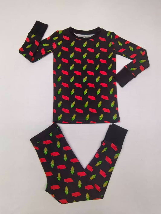 Children's pajama set with long sleeves, black base featuring red car and green leaf patterns.