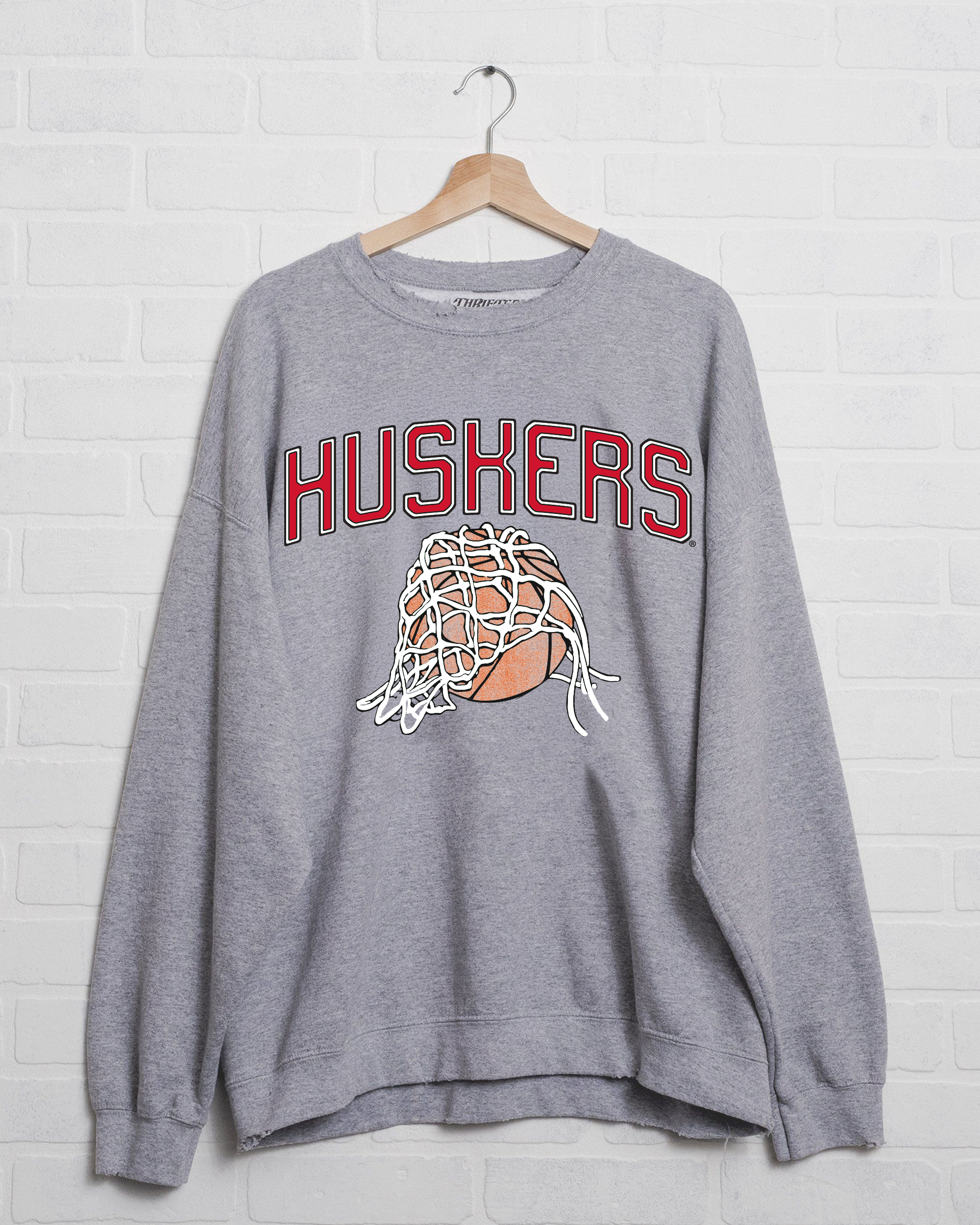 Gray sweatshirt with "HUSKERS" in red letters; features a basketball covered by a net. 